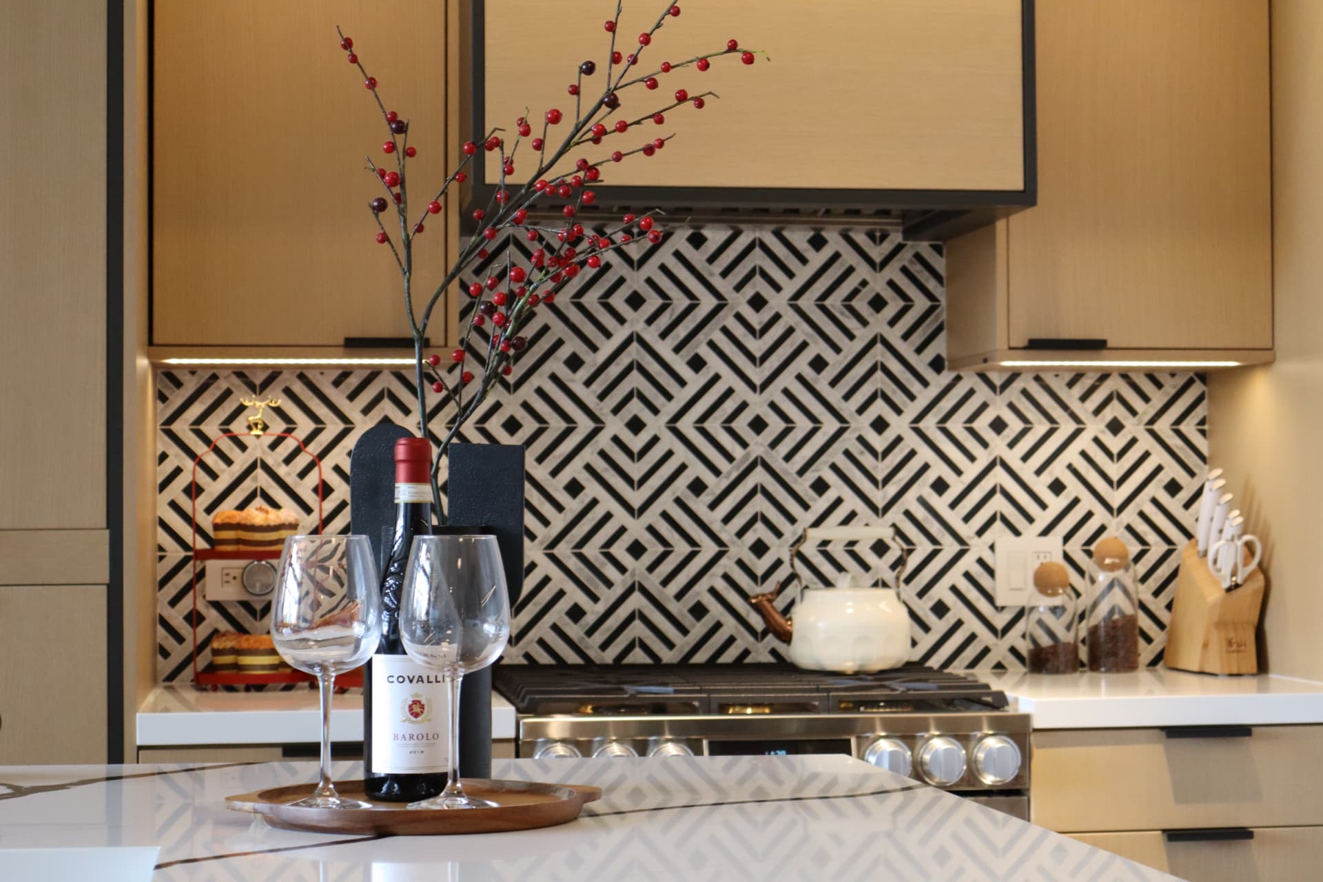 White oak cabinetry with black trim framing a geometric black and white tile backsplash over the range