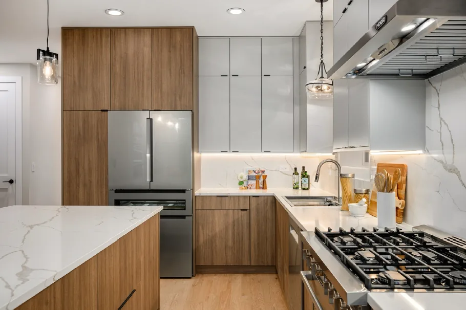 Kitchen combining warm wood cabinetry with a white marble island and counter stools