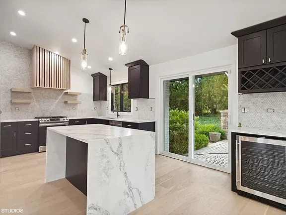 Open plan kitchen with a quartz waterfall island, integrated wine storage and glass doors to the garden